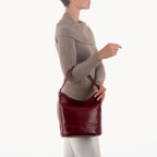 Person holding a red leather handbag against a white background