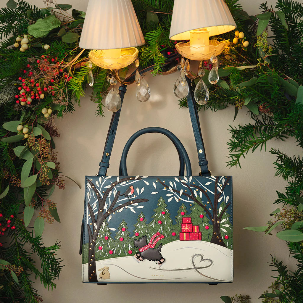 Decorative handbag with a winter scene design, surrounded by festive greenery and lights.