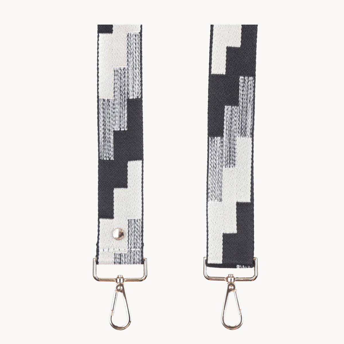 Two black and white patterned straps with metal hooks on a white background