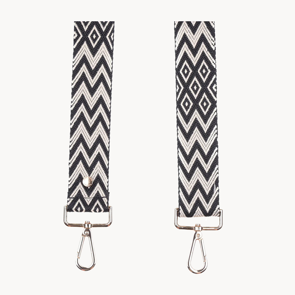 Two black and white patterned strap ends with metal hooks on a white background