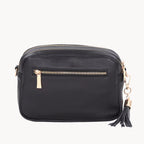 Black leather crossbody bag with gold zipper and tassel on a white background
