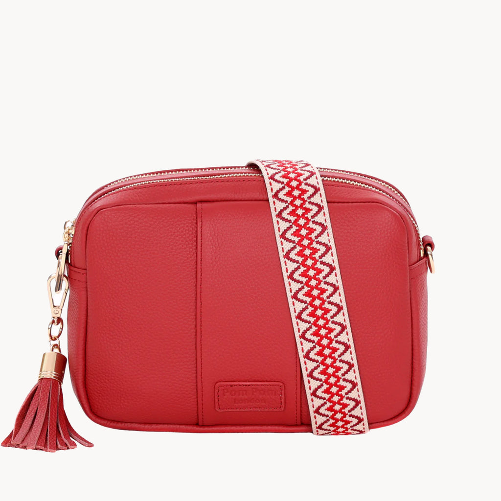 Red handbag with a patterned strap and tassel on a white background