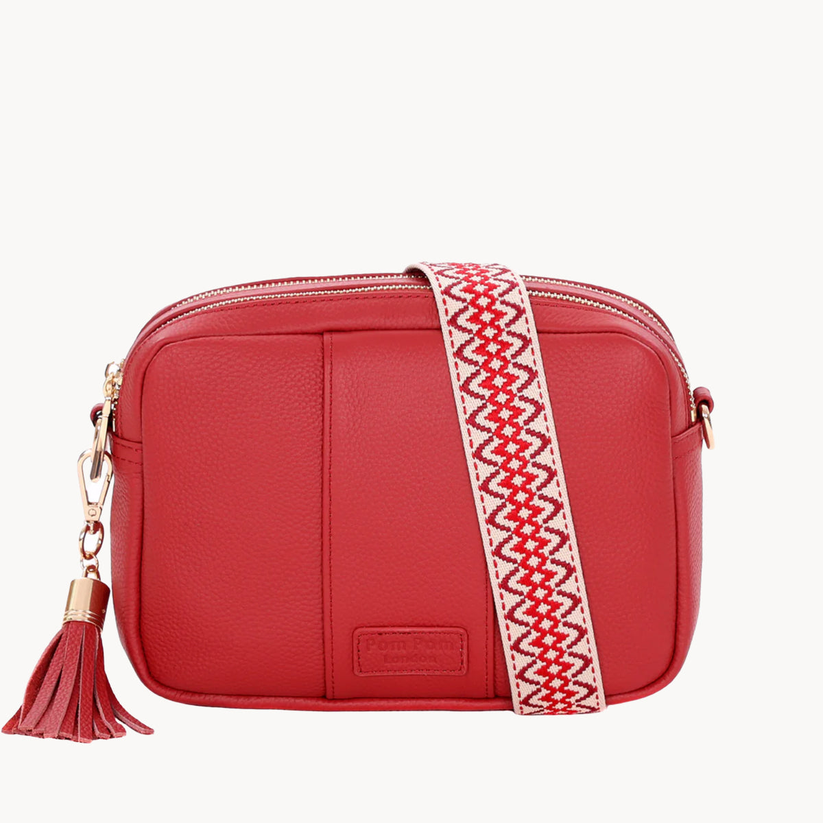 Red handbag with a patterned strap and tassel on a white background