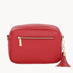 Red handbag with a gold zipper and tassel on a white background