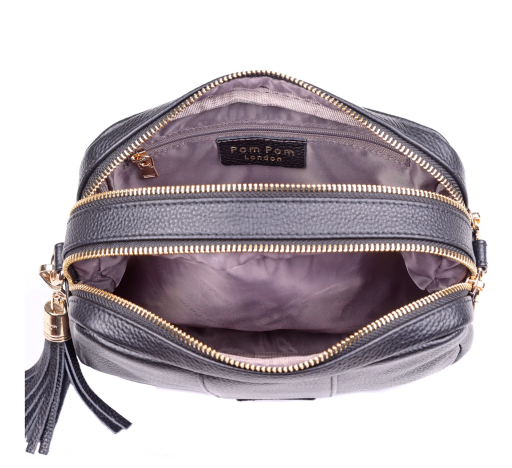 Gray handbag with gold zippers and a tassel on a white background, featuring the brand 'Pom Pom London'.
