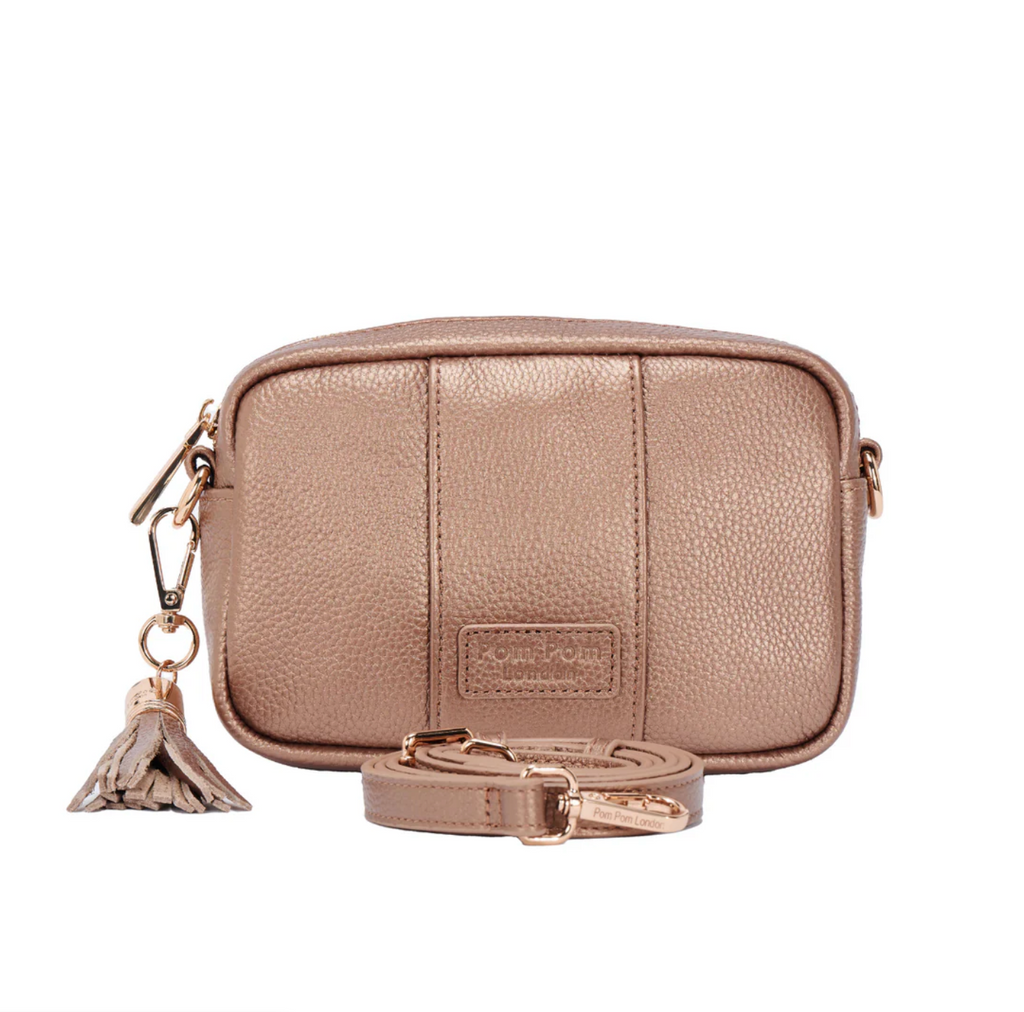 Bronze crossbody bag with a tassel charm on a white background and crossbody strap
