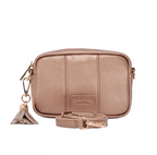 Bronze crossbody bag with a tassel charm on a white background and crossbody strap