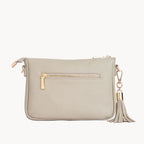 Stonehandbag with gold zipper and tassel on a light gray background