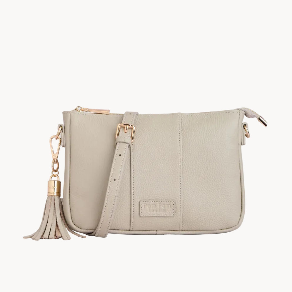 Stone handbag with gold accents and tassel on a light gray background