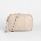 Beige crossbody bag with a tassel on a light gray background