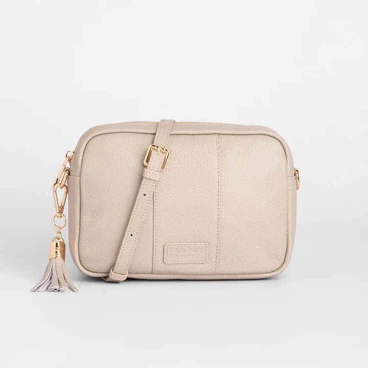 Beige crossbody bag with a tassel on a light gray background