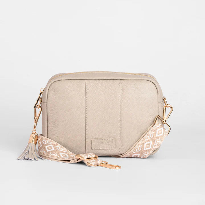 Beige crossbody bag with patterned strap on a light gray background