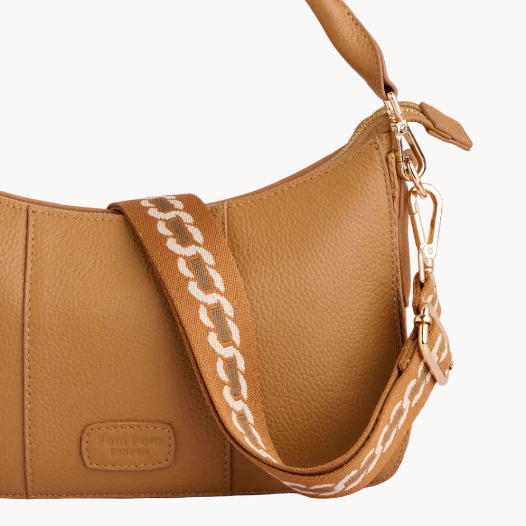 Tan leather handbag with chain detail on a light gray background