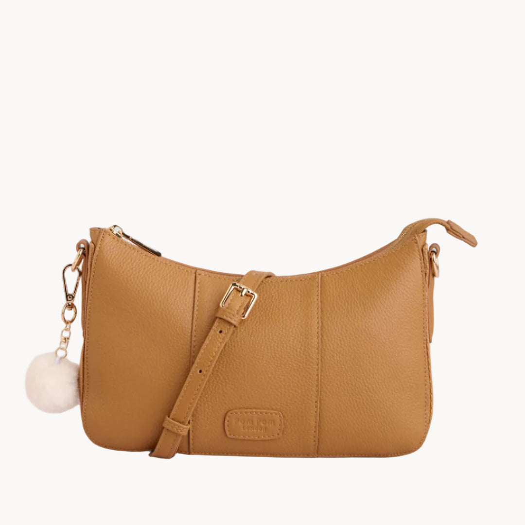 Tan leather handbag with a strap on a light gray background