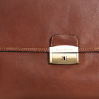 Close up of gold coloured front lock on tan leather briefcase