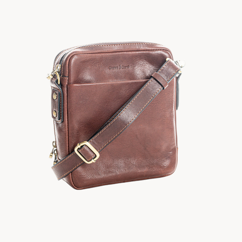 Brown leather crossbody bag with gold accents on a white background