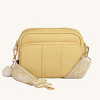 Yellow crossbody bag with a decorative band on a gray background