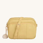 Yellow crossbody bag with a pom-pom on a gray background