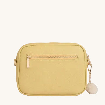 Yellow crossbody bag with a fluffy pom-pom on a light gray background