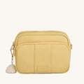 Yellow crossbody bag with a tassel on a gray background
