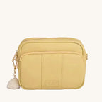 Yellow crossbody bag with a tassel on a gray background