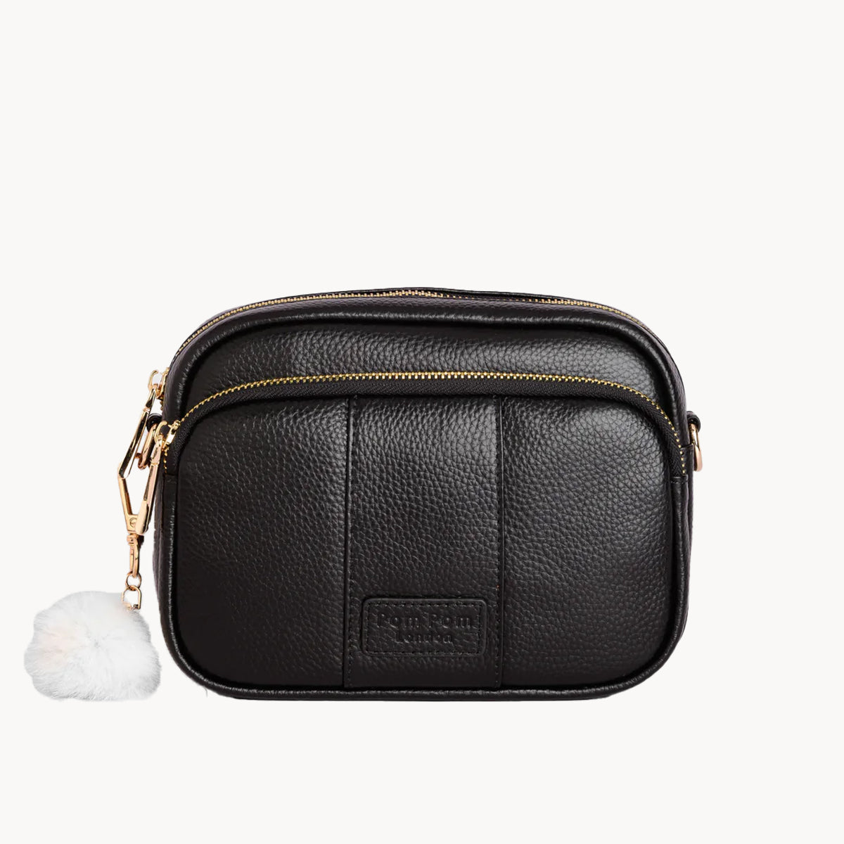 Black leather crossbody bag with a gold zipper and white pom-pom on a white background