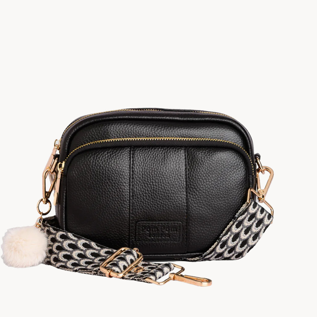 Black leather crossbody bag with a patterned strap on a white background