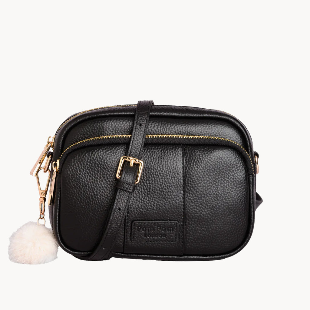 Black leather crossbody bag with a white pom-pom on a white background