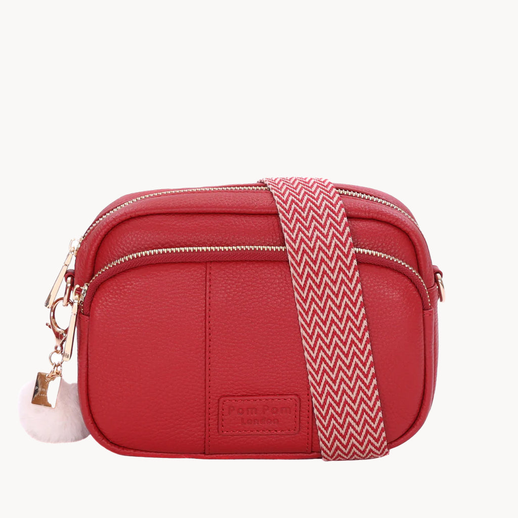 Red crossbody bag with a patterned strap on a white background