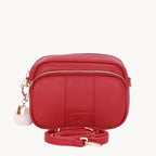 Red crossbody bag with a strap on a white background