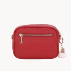 Red handbag with gold zipper and white tag on a white background