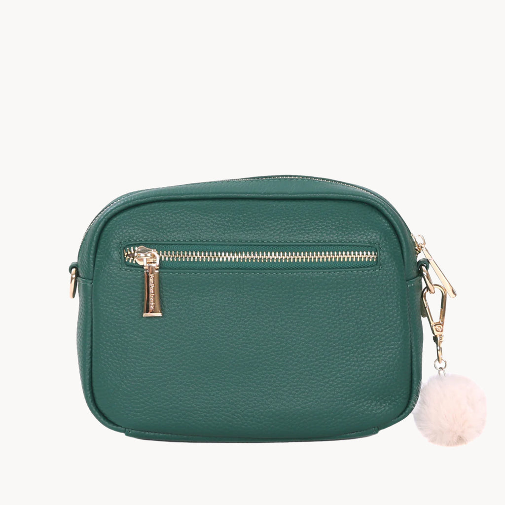 Green crossbody bag with gold zipper and pink pom-pom on a white background
