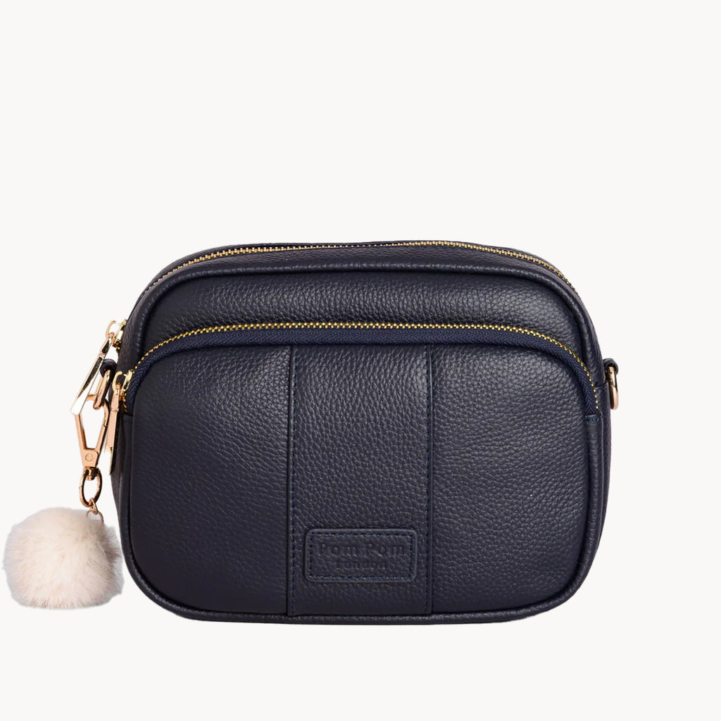 Black leather crossbody bag with a fluffy pom-pom on a white background