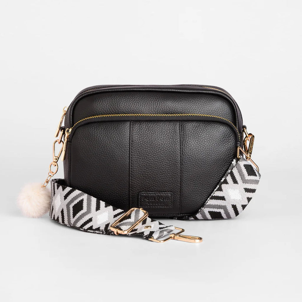 Black leather crossbody bag with a patterned strap on a white background