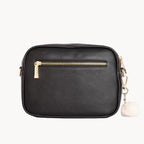 Black handbag with gold zipper and chain detail on a light gray background
