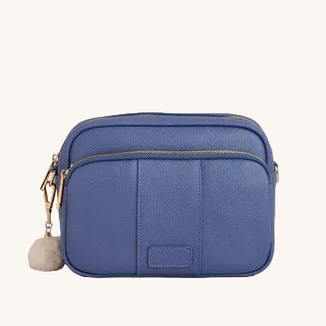 Blue crossbody bag with a pom-pom on a gray background