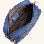 Blue leather bag with gold zipper on a light gray background