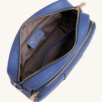 Blue leather bag with gold zipper on a light gray background