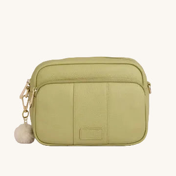 Green crossbody bag with a pom-pom on a light gray background