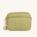 Green crossbody bag with a pom-pom on a light gray background