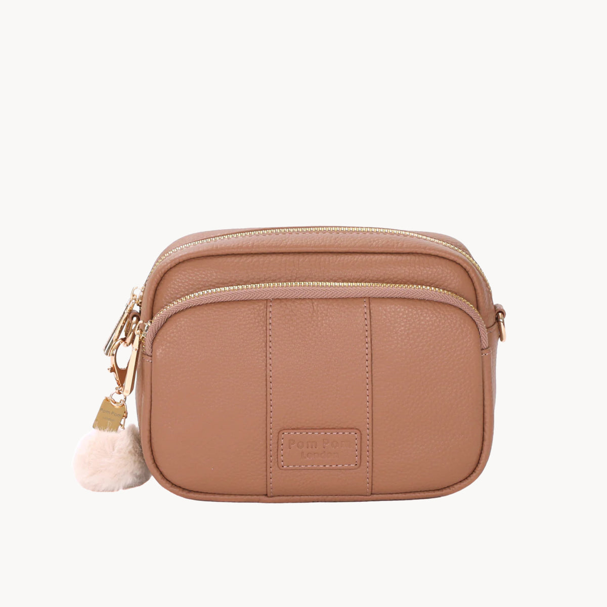 Brown leather crossbody bag with a pom-pom charm on a white background