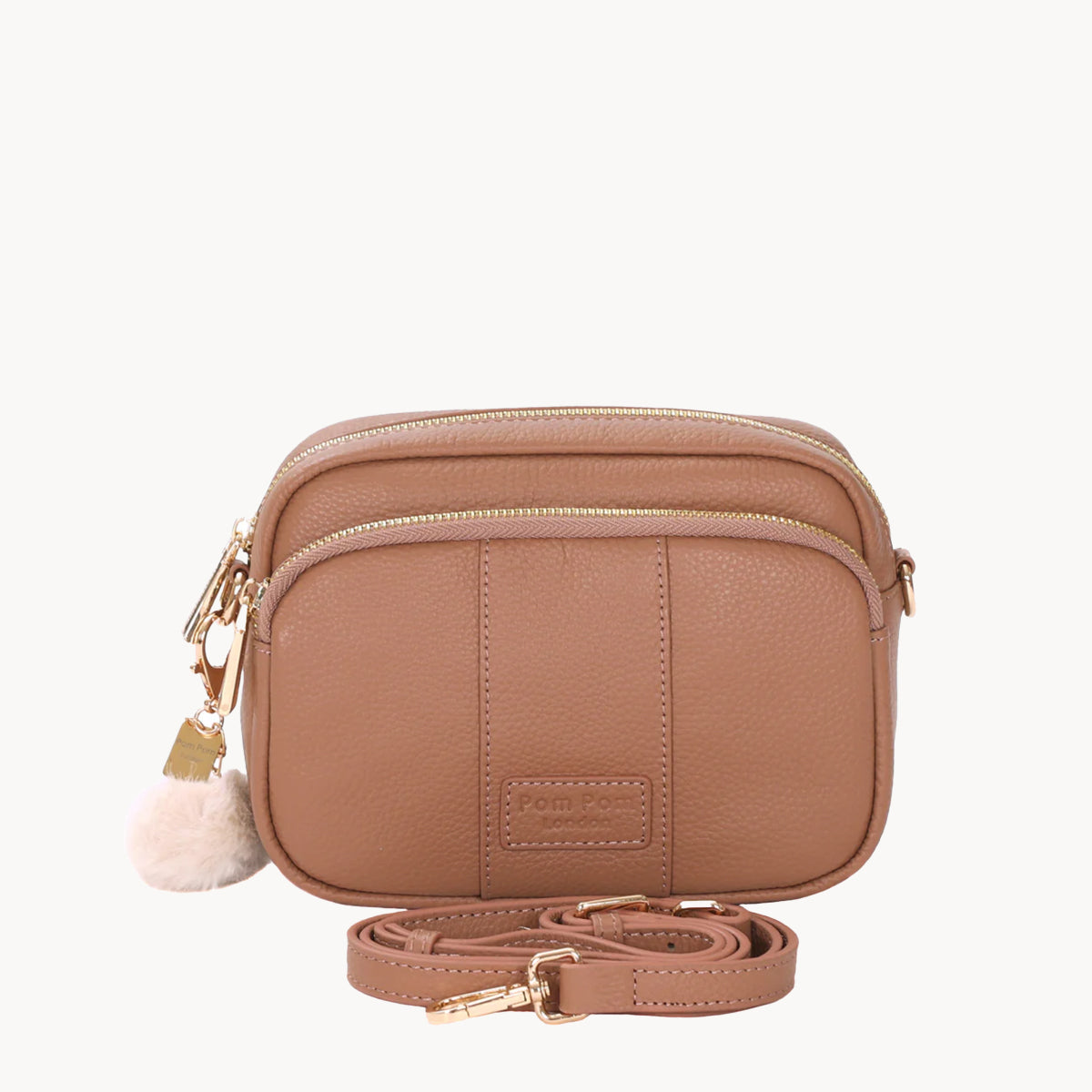 Brown crossbody bag with a strap and pom-pom detail on a white background