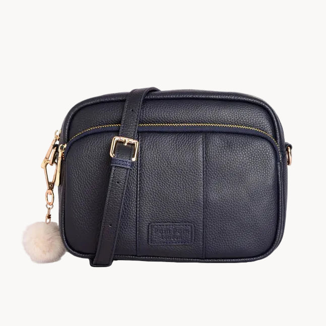 Navy leather crossbody bag with a visible brand label on a light gray background