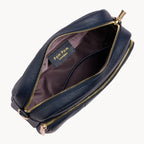 Navy leather crossbody bag with gold zipper on a light gray background