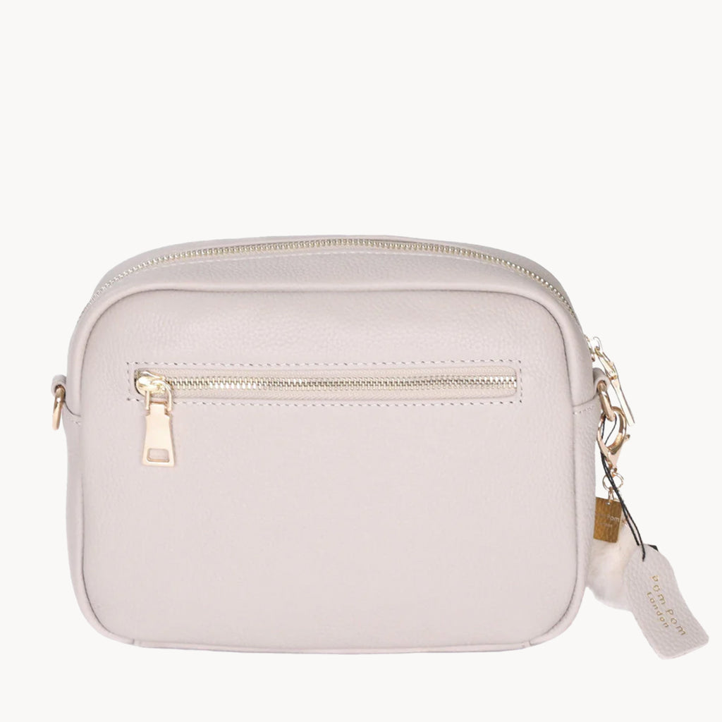 Stone crossbody bag with gold zipper and tag on a white background