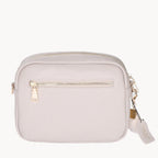 Stone crossbody bag with gold zipper and tag on a white background