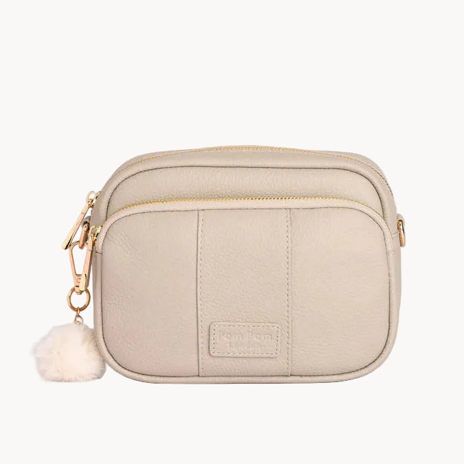 Stone crossbody bag with a fluffy pom-pom on a light gray background