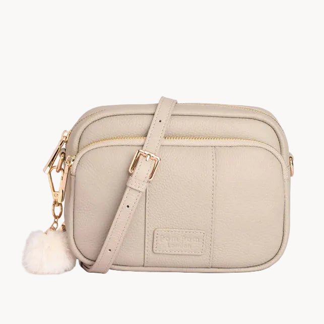 Stone crossbody bag with a white pom-pom on a light gray background