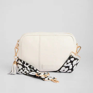 White handbag with a black and white floral strap on a light gray background