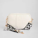 White handbag with a black and white floral strap on a light gray background